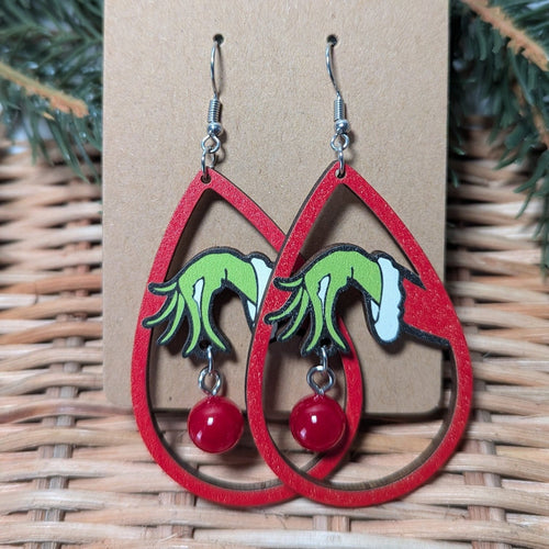 drop earrings with a grinch hand holding a bead like an ornament