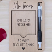 Load image into Gallery viewer, Wooden sticky note holder with a pen slot. Custom name and message are engraved on the piece. The quote &quot;big hearts teach little minds&quot; is also engraved.
