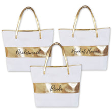 Load image into Gallery viewer, Three white tote bag with a gold handles and horizontal gold strips on the middle of the body of the bags. The words bridesmaid, maid of honor, and bride are located on each bag in black script.
